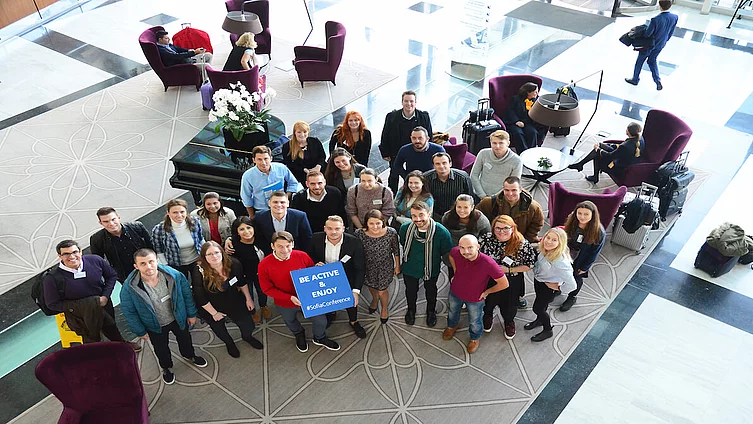 Gruppenfoto von Teilnehmenden an einer internationalen Jugendkonferenz in Sofia, die ein Schild mit der Aufschrift „Be Active & Enjoy Sofia Conference“ halten. 